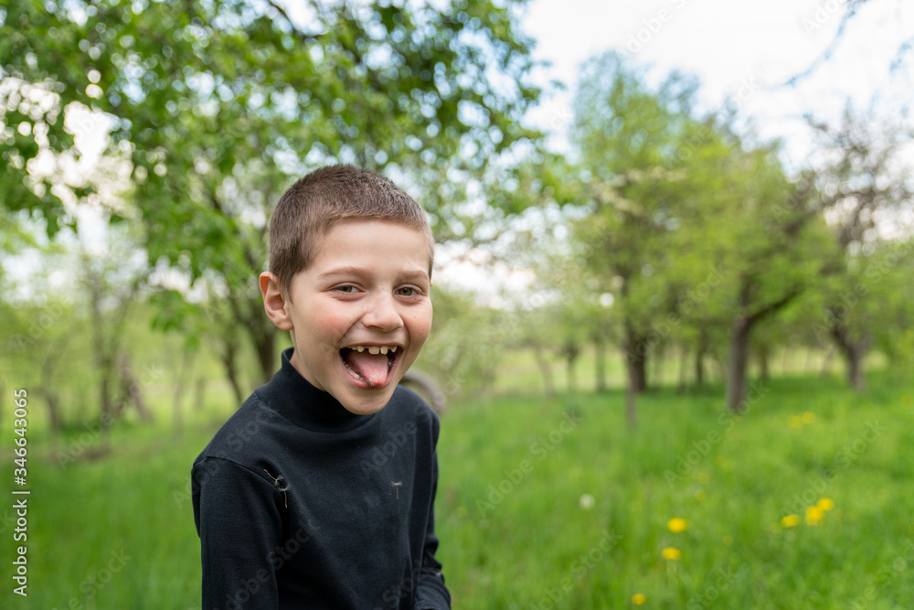 Happy little boy in black shirt shows tongue to the camera