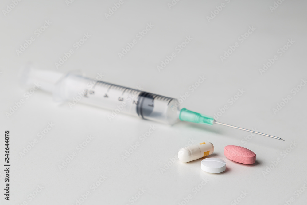 pills together with a medical syringe on a white background pills together with a medical syringe on a white background