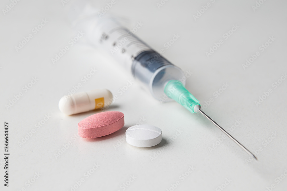 pills together with a medical syringe on a white background pills together with a medical syringe on a white background