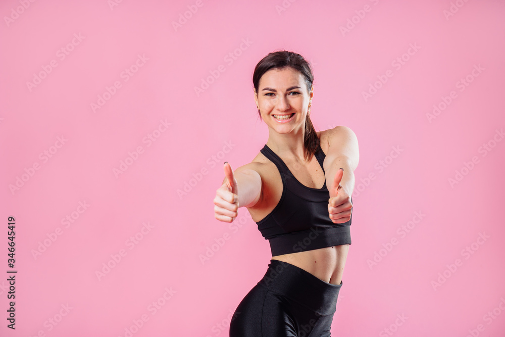 Diet and fitness concept - beautiful sporty woman showing thumbs up and her abs. Hand in the foreground shows a finger up gesture. Concept of female beauty and health, nutrition and beautiful figure Diet and fitness concept - beautiful sporty woman showing thumbs up and her abs. Hand in the foreground shows a finger up gesture. Concept of female beauty and health, nutrition and beautiful figure