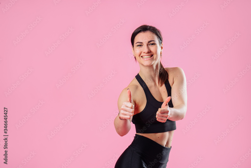 Diet and fitness concept - beautiful sporty woman showing thumbs up and her abs. Hand in the foreground shows a finger up gesture. Concept of female beauty and health, nutrition and beautiful figure Diet and fitness concept - beautiful sporty woman showing thumbs up and her abs. Hand in the foreground shows a finger up gesture. Concept of female beauty and health, nutrition and beautiful figure