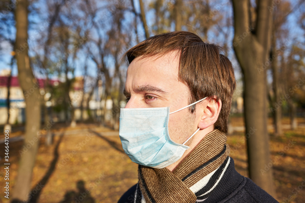 Portrait of young man with medical face mask stands at city street. Guy wearing protective mask from virus outdoor in the people crowdy. Portrait of young man with medical face mask stands at city street. Guy wearing protective mask from virus outdoor in the people crowdy.