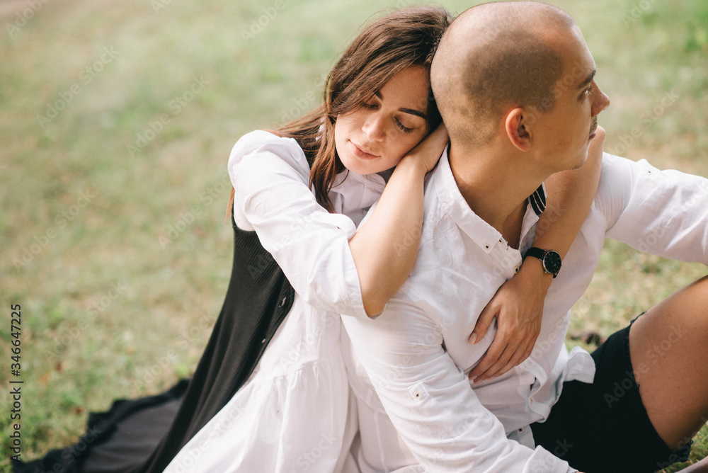 A porttret of a young caucasian stylish couple sitting on beautiful park A porttret of a young caucasian stylish couple sitting on beautiful park