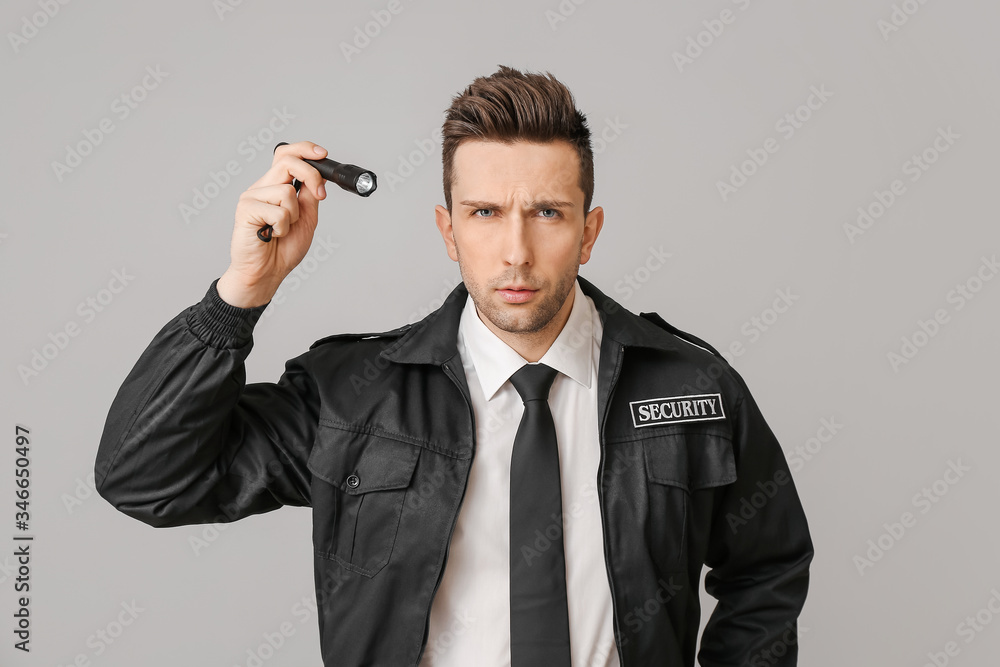 Male security guard with flashlight on grey background Male security guard with flashlight on grey background