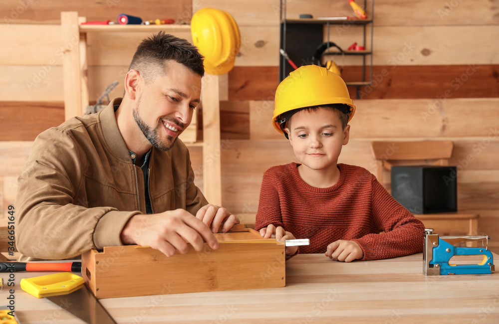 Little son helping his father in carpenter's workshop Little son helping his father in carpenter's workshop