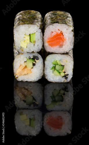Set of four classic sushi rolls isolated on black backround with reflection. Salmon, avocado, eel, cucumber, sesame