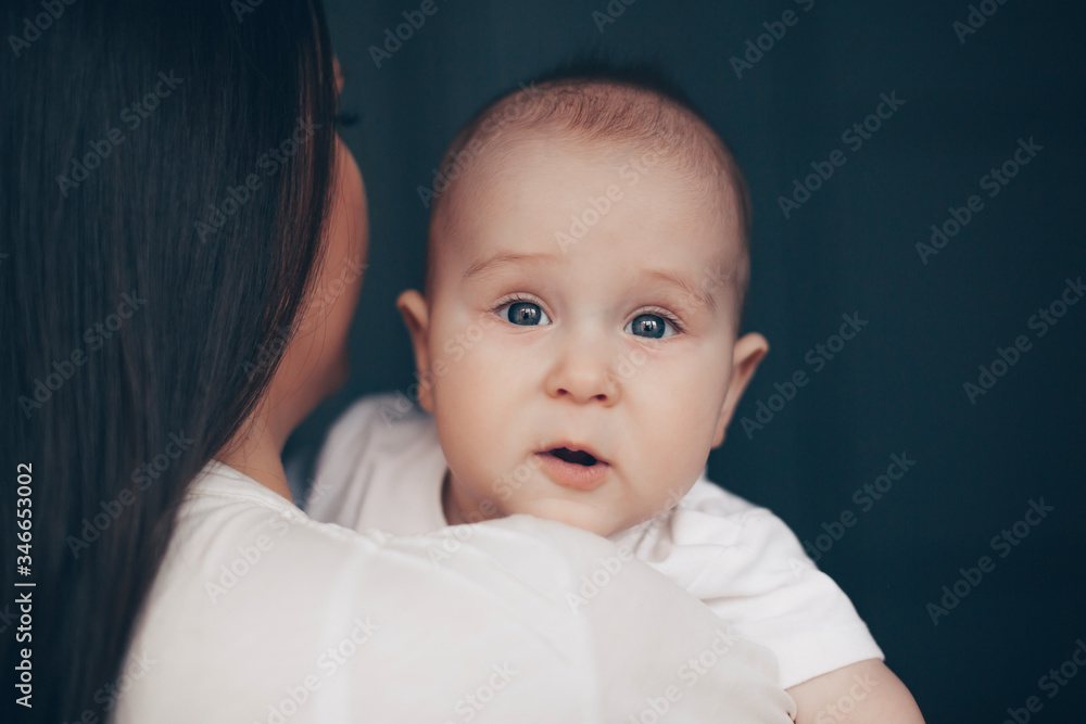 Close-up portrait of a serene cute beautiful baby boy on mother's hands on dark background. Healthcare and medical love woman mother's day concept. Close-up portrait of a serene cute beautiful baby boy on mother's hands on dark background. Healthcare and medical love woman mother's day concept.