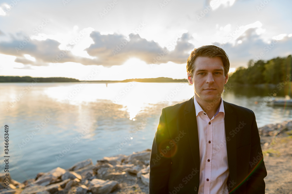 Young handsome businessman in front of beautiful scenic shore with lens flare Young handsome businessman in front of beautiful scenic shore with lens flare