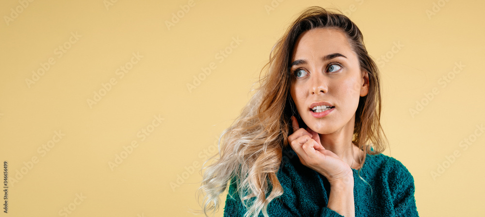 Fototapeta premium Woman excited looking to the side. Surprised happy young woman looking sideways in excitement on yellow background