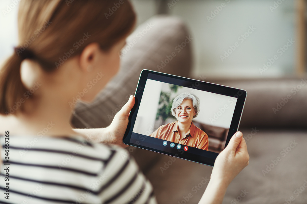 Young woman having video call with eldery mother on tablet - obrazy, fototapety, plakaty 