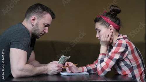 A man and a woman are sitting at the table and counting the rest of the money. A difficult period in a young family.