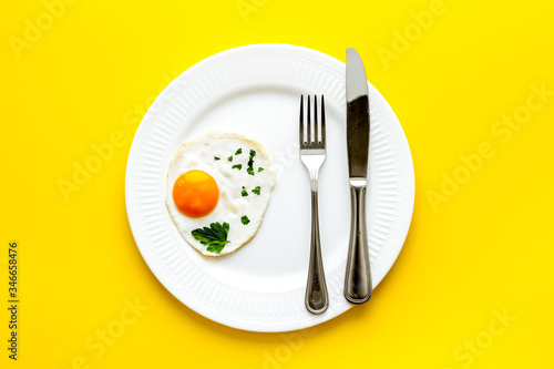 Fried egg on plate on yellow table top view copy space