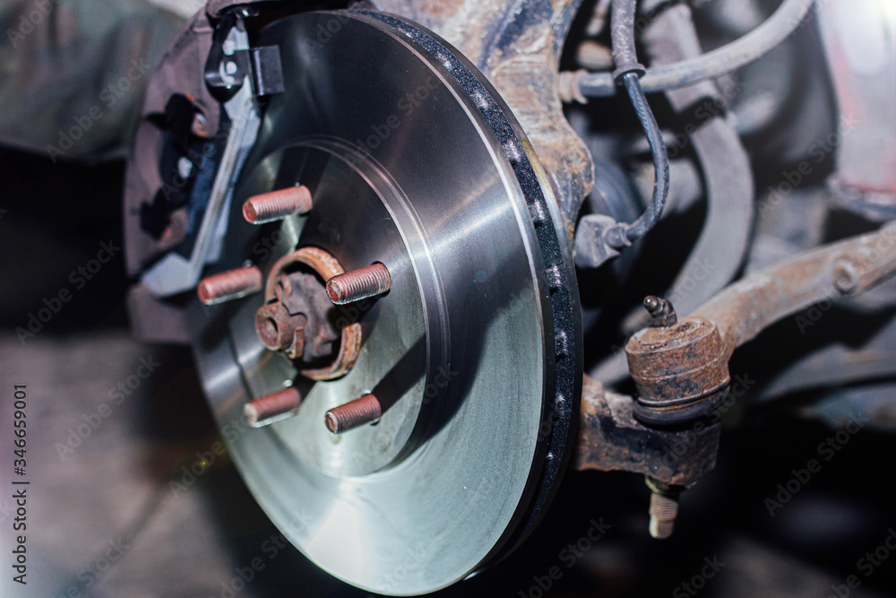 Fototapeta premium installation of a ventilated brake disc of a car on a hub in a garage. brake system repair