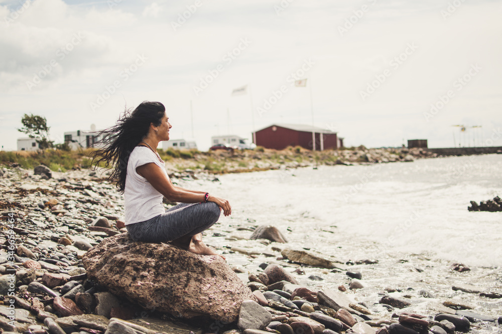 woman meditating and doing yoga on a rock
