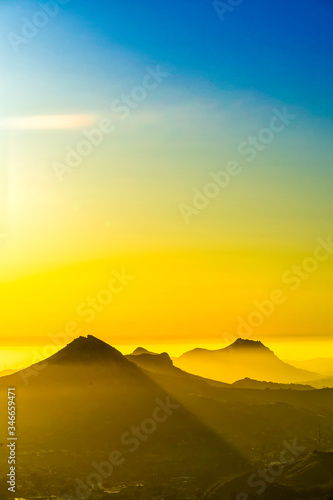 Silhouetted Mountain at Sunset with Yellow Rays 