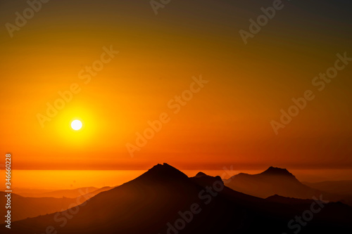 Setting Sun over Silhouetted Mountains, Layer of Fog 