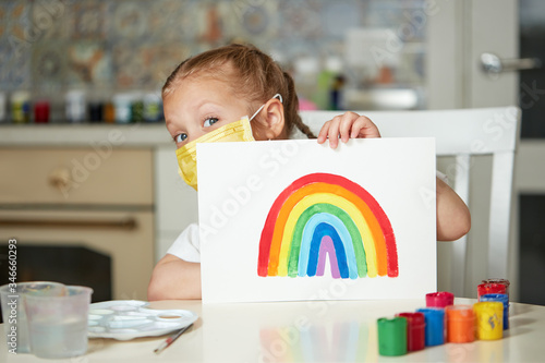 Thank to NHS. Kid in protective mask painting the rainbow during Covid-19 quarantine at home. coronavirus covid-19 outbreak. photo