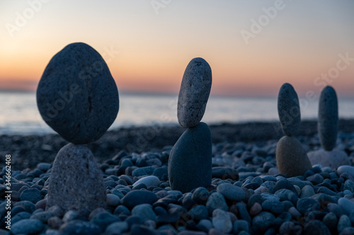 Summer is coming soon in a pandemic. Deserted city beach on the Black Sea. Sculptures of stones  a symbol of people. Stone people. Imitation of lovers. Art installation from pebbles. Meditation at sea