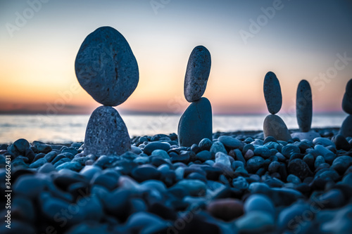 Summer is coming soon in a pandemic. Deserted city beach on the Black Sea. Sculptures of stones, a symbol of people. Stone people. Imitation of lovers. Art installation from pebbles. Meditation at sea