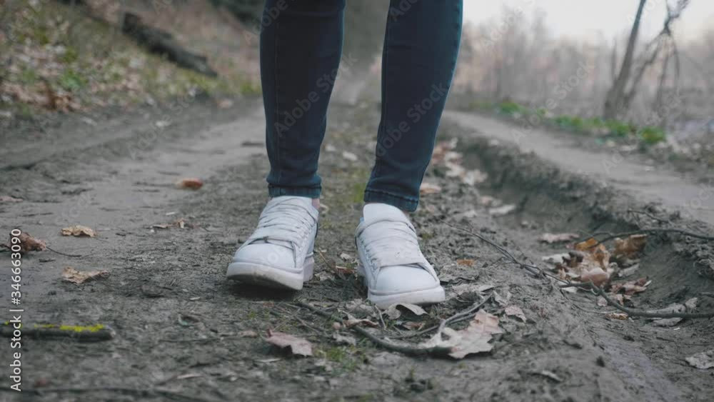 Focus on white sneakers. Active healthy woman hiking in autumn forest. Recreation and healthy lifestyle outdoors in nature. Focus on white sneakers. Active healthy woman hiking in autumn forest. Recreation and healthy lifestyle outdoors in nature.