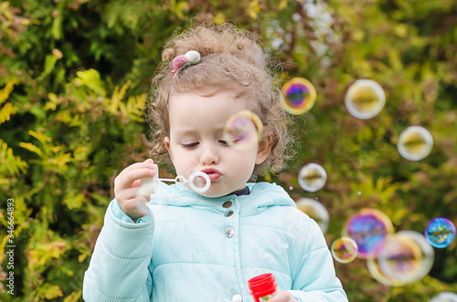 portrait of happy little beautiful girl blowing out soap bubbles on natura. children's leisure. funny outdoor games