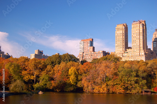 Fall foliage surrounds a lake in Central Park, with the skyline of the Upper West Side rising behind it