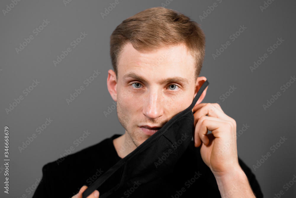 Handsome man in black t-shirt wear black medical mask, gray background. Coronavirus covid-19 quarantine period concept. Handsome man in black t-shirt wear black medical mask, gray background. Coronavirus covid-19 quarantine period concept.