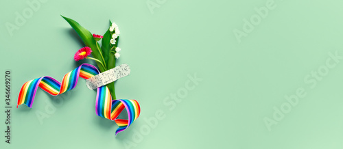 Thank you doctors and nurses! Rainbow ribbon and bouquet of red primrose and lily of the valley flowers attached with medical aid patch. Creative panoramic flat lay on green background, text space. photo