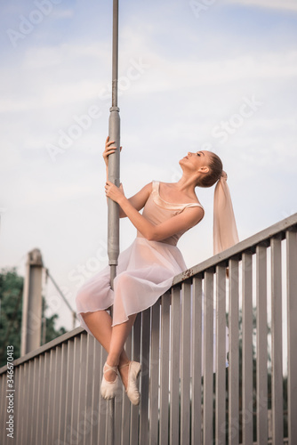 Ballerina girl with long hair sits on a white bridge