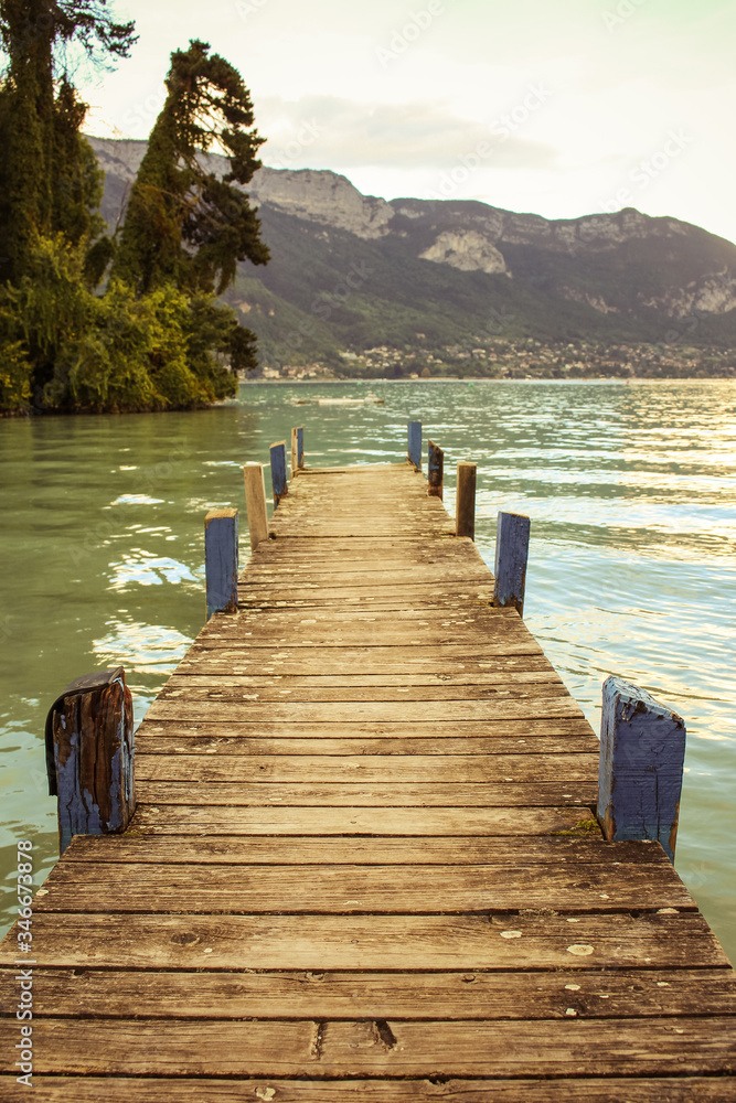 Lakefront of Annecy (Jardins de l’Europe) at sunset. An old wooden pier faces the mountain of La Tournette and the sharp rocky ridges of the Dents de Lanfon.