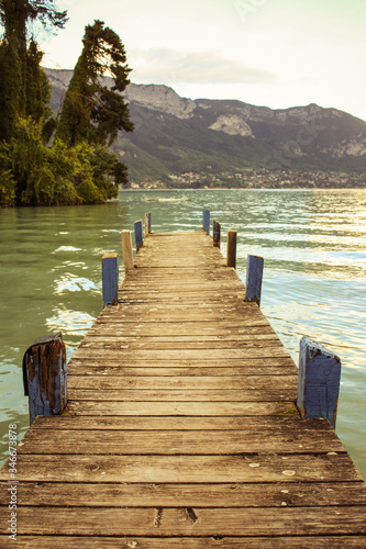 Obraz na płótnie Lakefront of Annecy (Jardins de l’Europe) at sunset. An old wooden pier faces the mountain of La Tournette and the sharp rocky ridges of the Dents de Lanfon. w salonie