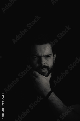 Bearded man face on a black backgroud in low key © Diego