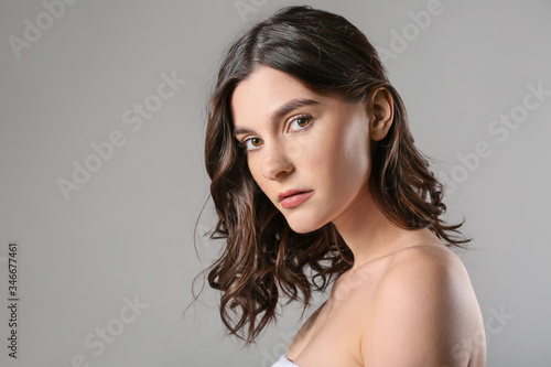 Young woman with beautiful short wavy hair on grey background