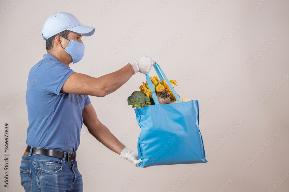 Mexican delivery man delivering grocery bag wearing face mask and gloves Mexican delivery man delivering grocery bag wearing face mask and gloves