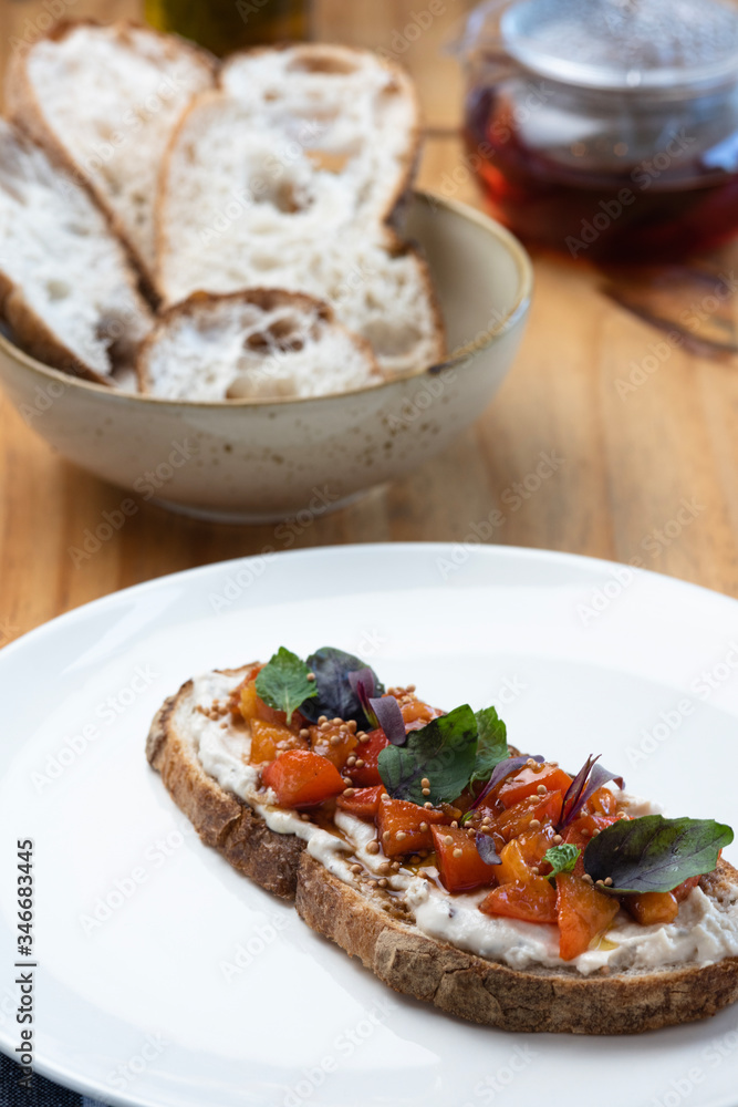 Breakfast table with natural fermentation toast with vegan curd, tomatoes and basil. Vegan food