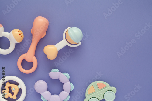 Flat lay composition with baby rattles set in pastel colors and space for text on lilac background. photo