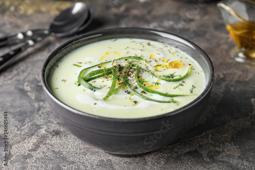 Bowl with cold cucumber soup on dark background photo