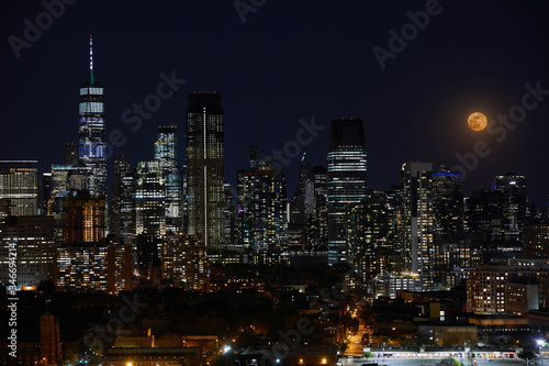 A full moon and night sky over a downtown city skyline.