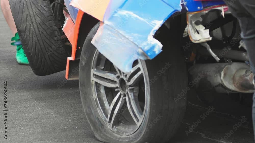 Totally wrecked car is being towed by a tow truck. Close up rear left wheel Totally wrecked car is being towed by a tow truck. Close up rear left wheel
