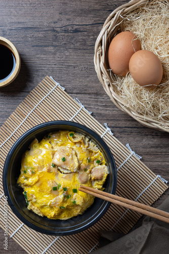 Oyako-don rice bowl topped with chicken, onions and egg cooked with special sauce. oyakodonburi Japanese food on wooden background. top view. Flat lay. photo