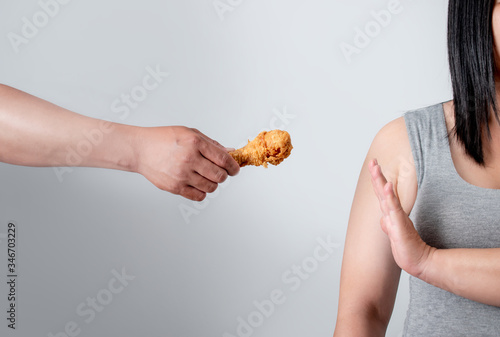 Overweight young women reject fried food. She is losing weight on a white background.