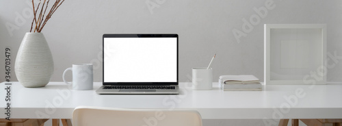 Close up view of minimal worktable with mock-up laptop, mug, supplies and decoration with chair