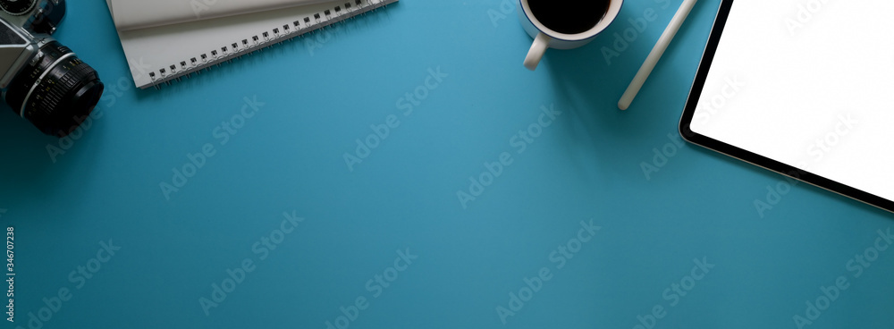 Top view of creative workspace with blank screen tablet, coffee cup, diary notebooks, camera and copy space Top view of creative workspace with blank screen tablet, coffee cup, diary notebooks, camera and copy space