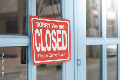 A Sign board of sorry we are closed of business shop with Blue door