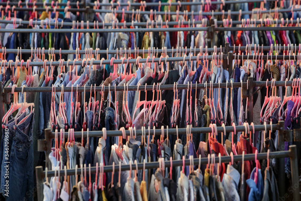 Foto de Huge selection of different used clothes for men, women and  children on the rack in a second hand shop or thrift store. Concept of  waste problem in fashion industry. do