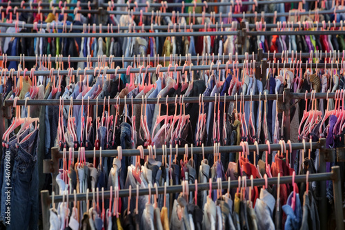 Huge selection of different used clothes for men, women and children on the rack in a second hand shop or thrift store. Concept of waste problem in fashion industry.