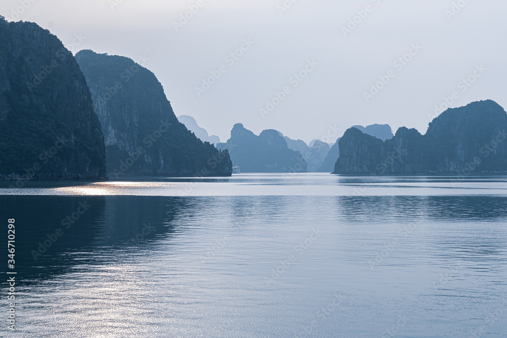 Islands and rocks of Halong Bay in misty low light.
