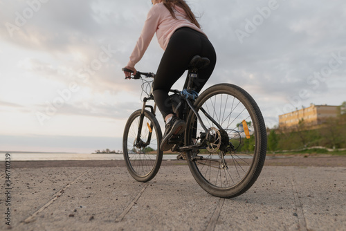 A young beautiful girl-athlete goes in for sports and leads a healthy lifestyle, so every morning she rides a bicycle to the sea.
