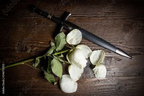 A wilted rose on a distressed wooden tabletop with other items