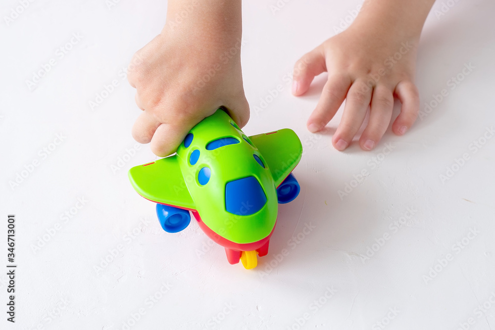 A small child holds a green toy airplane. The concept of imagination, children's games, travel, leisure, tourism